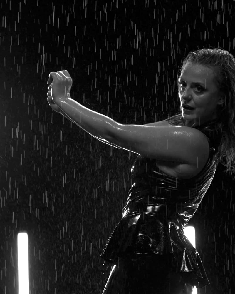 Model i latexkjole danser i regnen, fra DK Productions kampagnefilm 2025